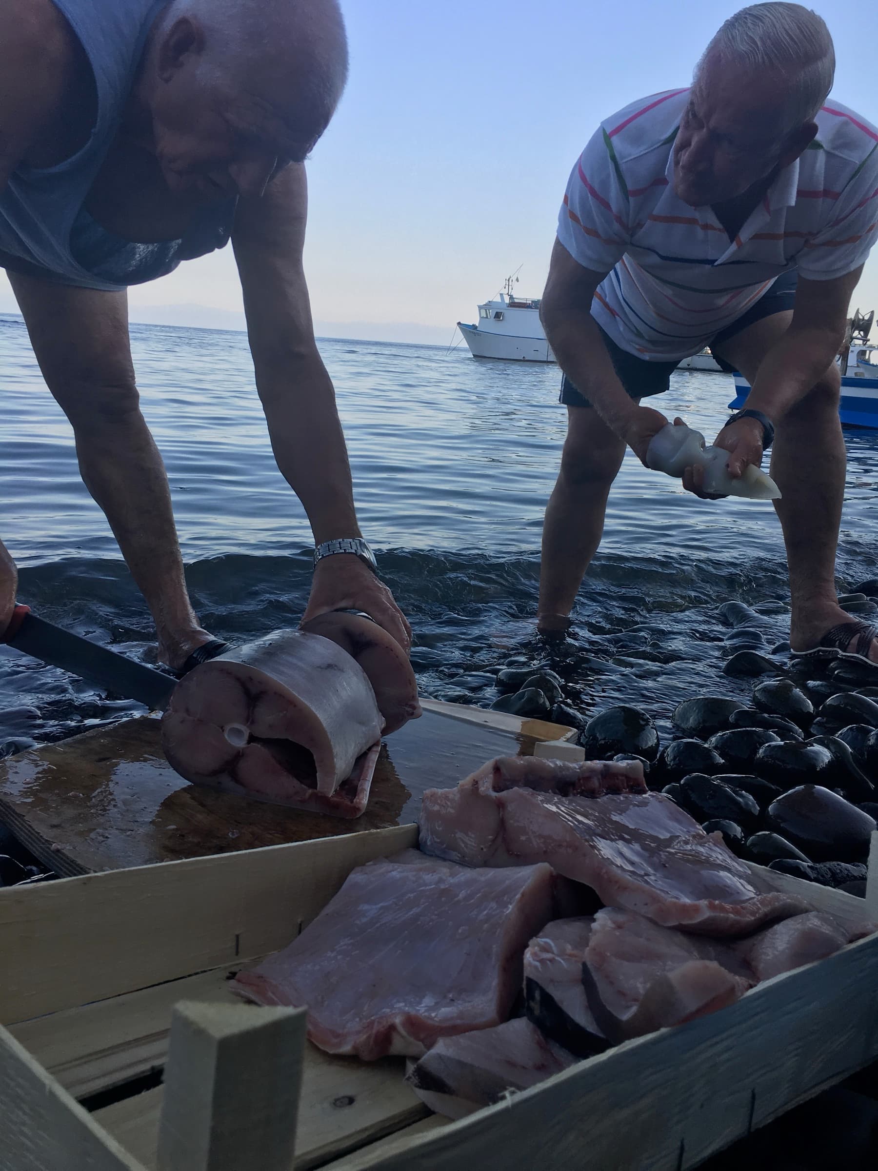 Zwei Fischer am Wasser, beim Zerteilen des Tagesfangs