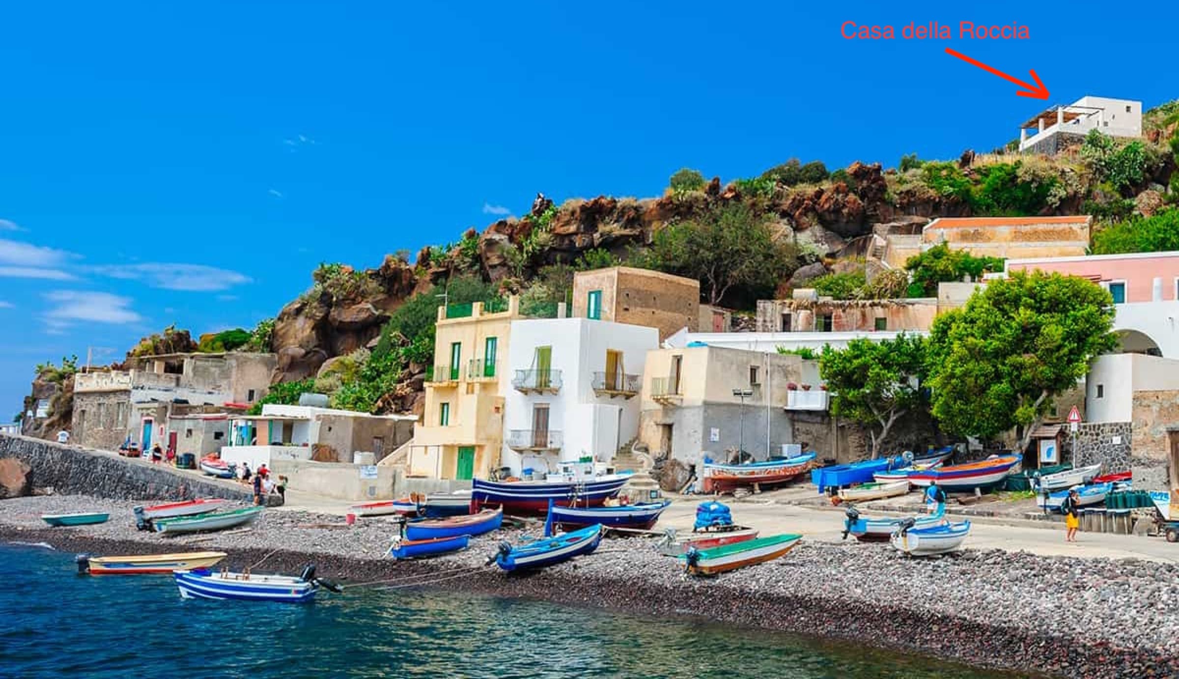 Le port d'Alicudi vu depuis la mer, avec une flèche rouge indiquant l'emplacement de La Casa della Roccia